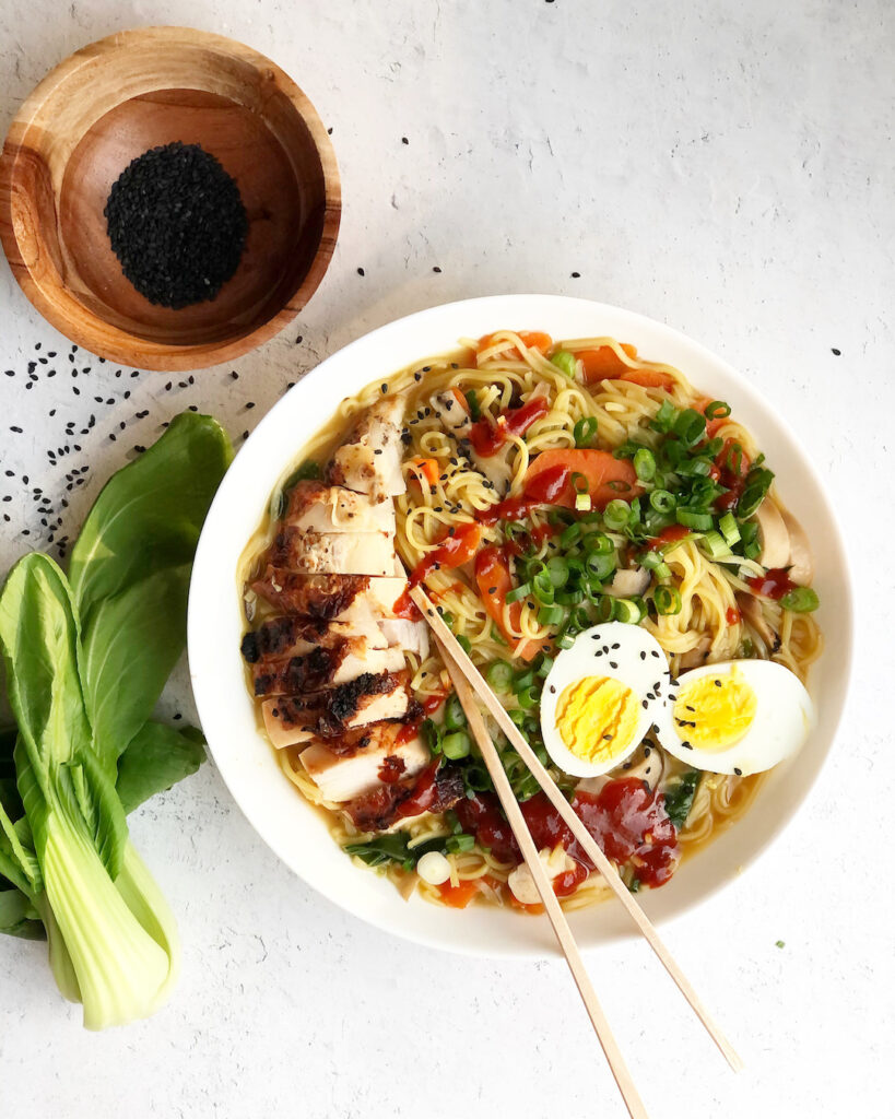 ramen in a bowl with chop sticks and bock choy and sesame seeds