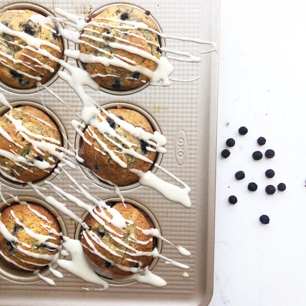 muffins in a pan with glaze drizzled. 