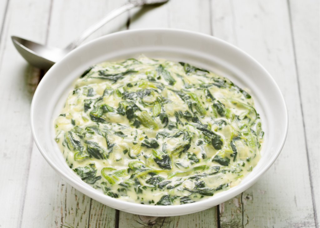 creamed spinach in a white bowl with spoon