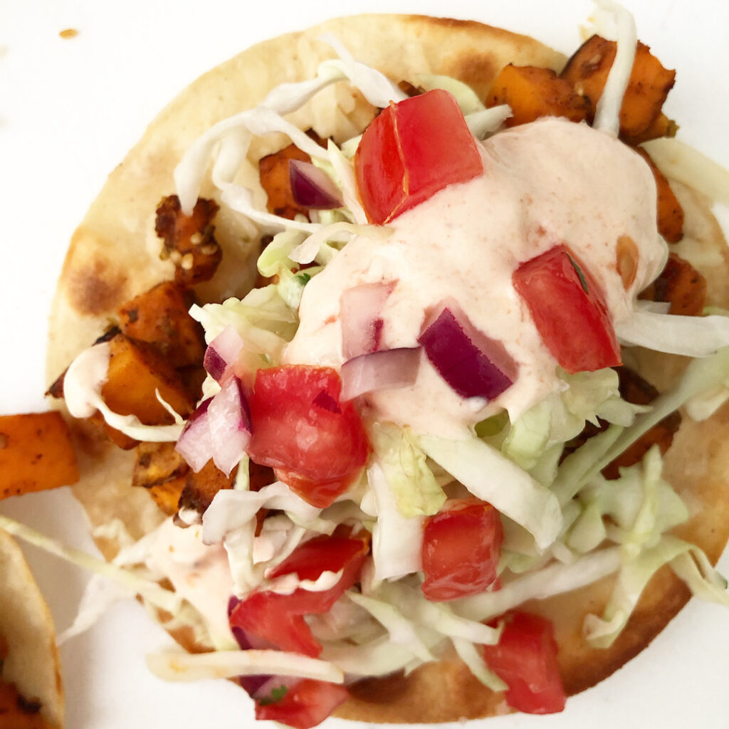 sweet potato taco topped with cabbage, crema and pico de gallo