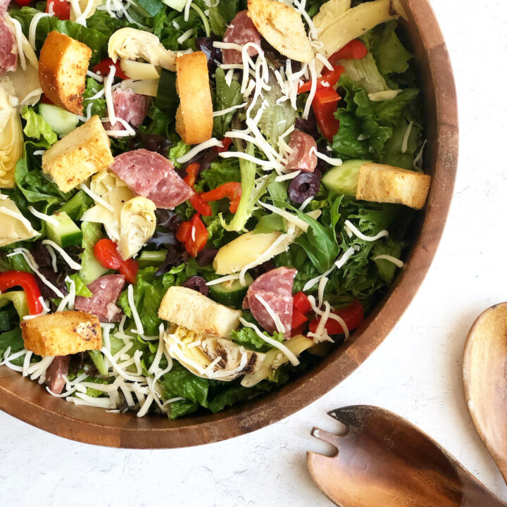 Antipasto salad in wood bowl with wooden salad spoons